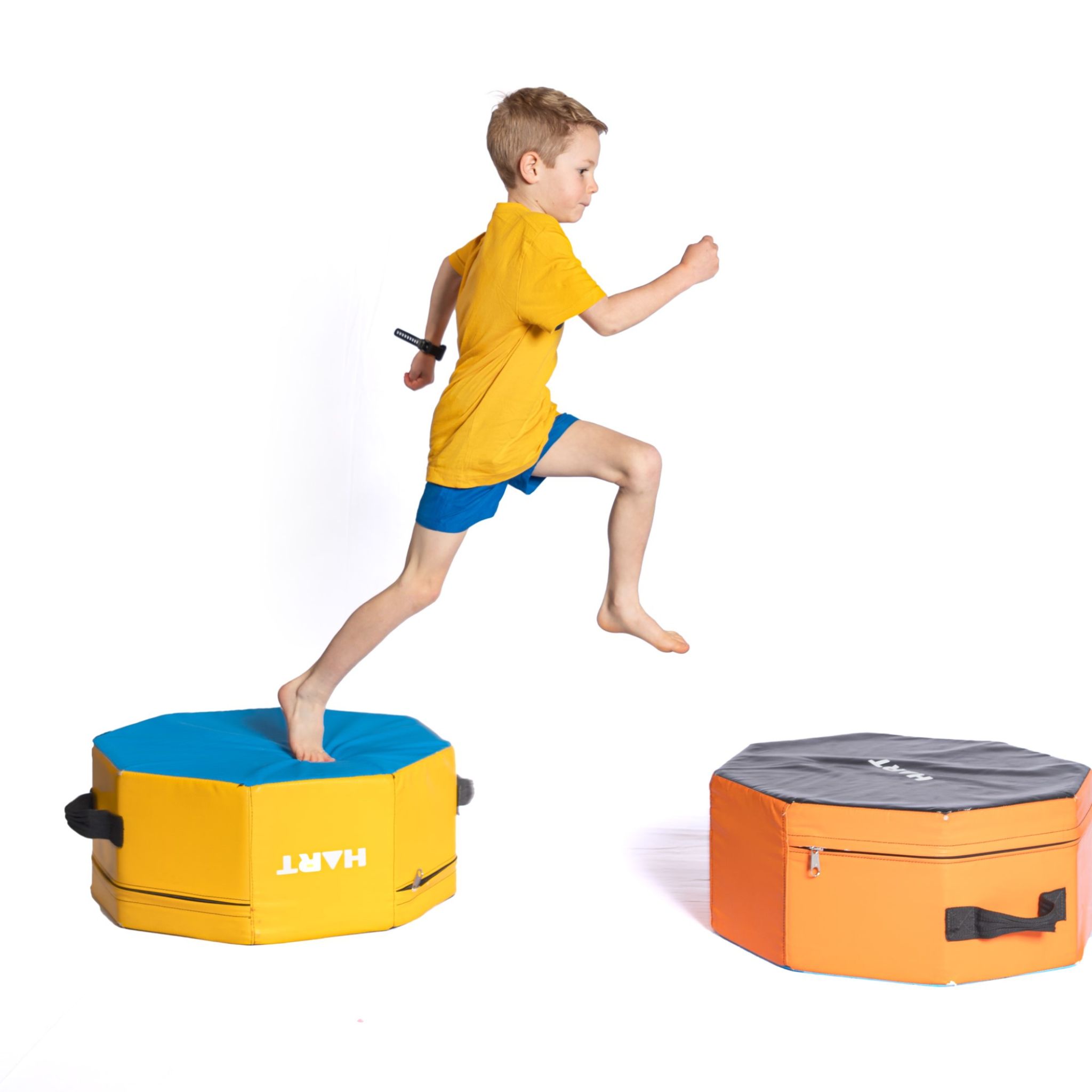 Three young kids crawling through a foam cylinder looking at camera.